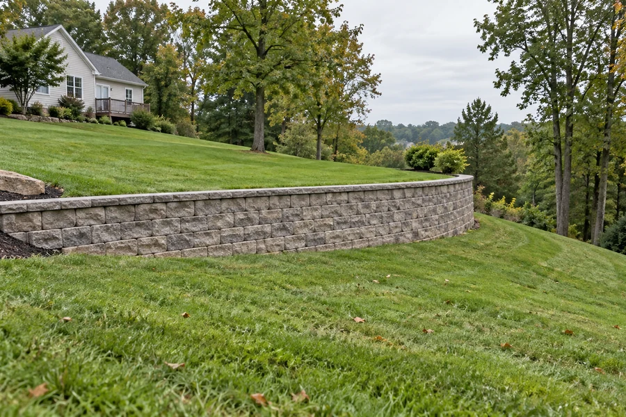 Curved block retaining wall creating an upper lawn terrace on a sloping residential yard